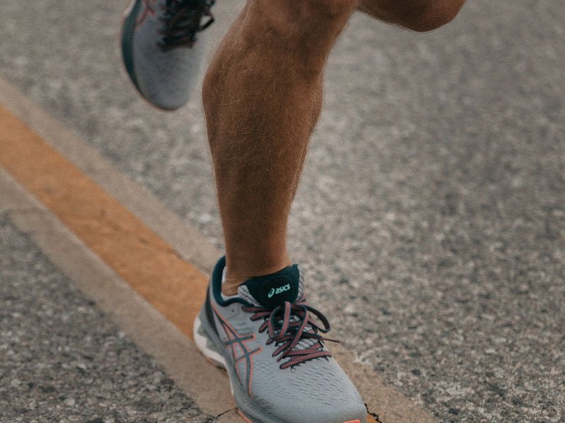 Athletic man running sneakers on road