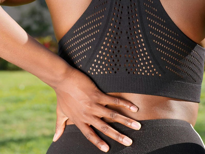 Female athlete holding left lower back pain